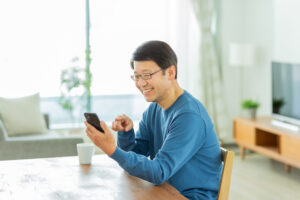 自宅のテーブルでスマートフォンを見る男性