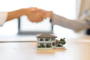 住宅の模型を前にした握手
