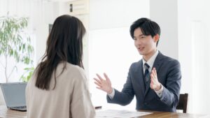 テーブル越しに説明する担当者と女性