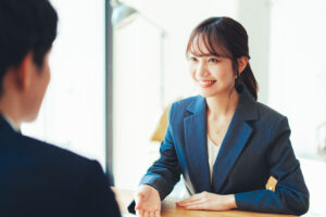 テーブル越しに笑顔で応対する女性担当者